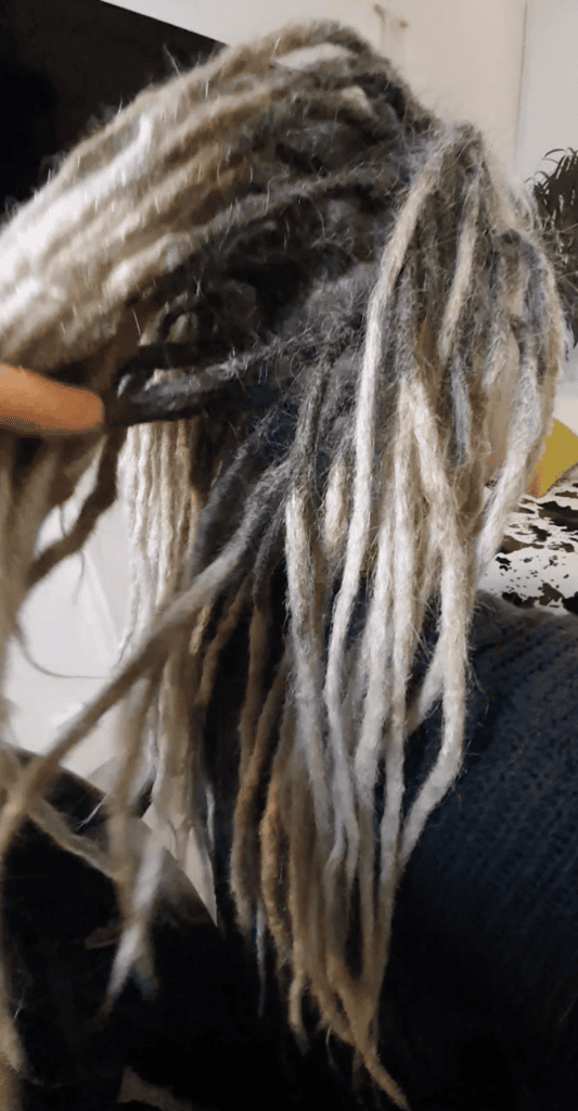 Specialist checking permanent dreadlock extensions during long-term maintenance